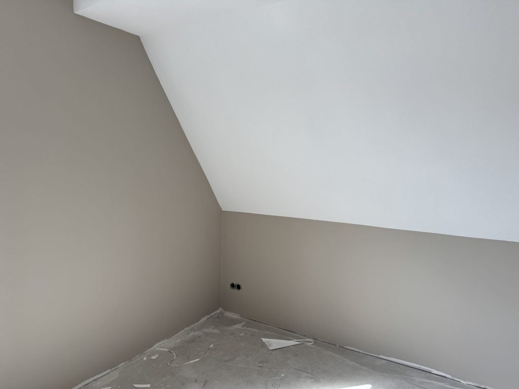 Zolderkamer met een schuine wand, de muren in een zachte grijstint afgewerkt