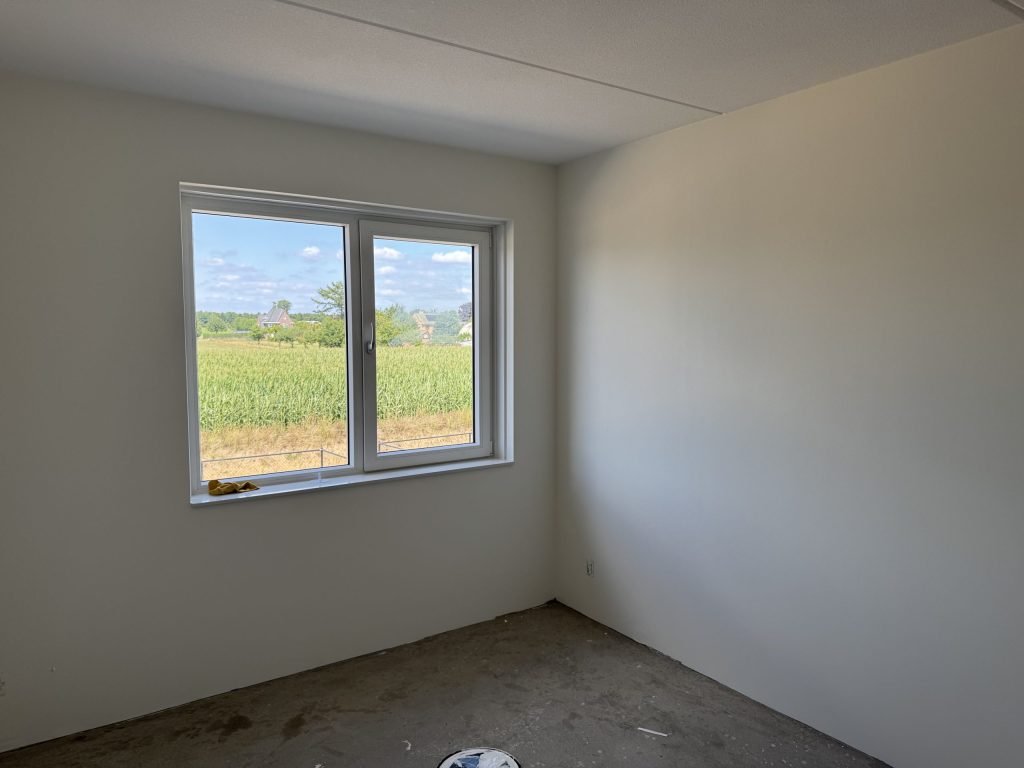 Lege kamer met gladde lichte wanden en een raam met uitzicht op een veld