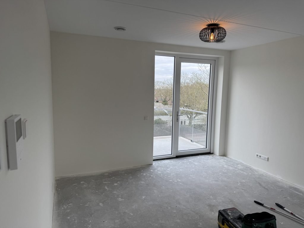 Leeg appartement met gladde lichte wanden en openslaande deuren naar het balkon